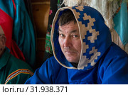 Традиционный обрядовый праздник восточных ханты «Медвежьи игрища». Мужчина ханты наблюдает за сценками. The traditional ritual celebration of the Eastern Khanty "The Bear games». 03.21-24.2016. Khanty man watching scenes. Редакционное фото, фотограф Евгений Романов / Фотобанк Лори