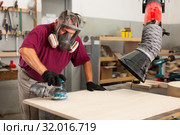 Worker grinds the wood plank of angular grinding machine. Стоковое фото, фотограф Яков Филимонов / Фотобанк Лори