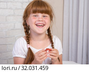 Маленькая рыжеволосая девочка  в белом платье держит в руках пластинку для исправления прикуса зубов. Стоковое фото, фотограф Гетманец Инна / Фотобанк Лори