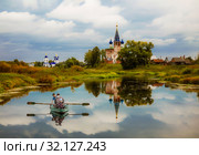 Сельский пейзаж с церквями, рекой Теза и людьми в лодке. Село Дунилово, Шуйский район Ивановской области. Россия (2019 год). Редакционное фото, фотограф Наталья Волкова / Фотобанк Лори