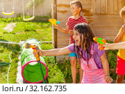 Summer fun - girl shoot water gun in group of kids. Стоковое фото, фотограф Сергей Новиков / Фотобанк Лори