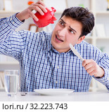Man running out of money in restaurant and using savings from pi. Стоковое фото, фотограф Elnur / Фотобанк Лори