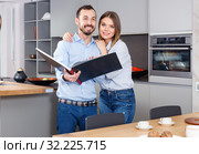 Young beautiful couple standing with book in modern kitchen inte. Стоковое фото, фотограф Яков Филимонов / Фотобанк Лори