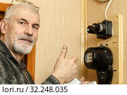 The man takes the readings of the apartment electric meter and writes it in the notebook. Стоковое фото, фотограф Акиньшин Владимир / Фотобанк Лори