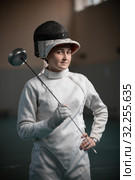 A young woman fencer with an open helmet on standing in the gym. Стоковое фото, фотограф Константин Шишкин / Фотобанк Лори