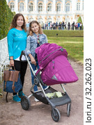 Mother with newborn baby in stroller and big sister standing in summer park, Caucasian people. Стоковое фото, фотограф Кекяляйнен Андрей / Фотобанк Лори