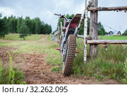 Recreational off-road motorcycle leaning to rural wooden fence in village, rear view. Стоковое фото, фотограф Кекяляйнен Андрей / Фотобанк Лори