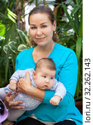 Adult mother holding baby in her arms, two month old infant with young woman in greenhouse. Стоковое фото, фотограф Кекяляйнен Андрей / Фотобанк Лори