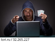 Young man wearing a hoodie sitting in front of a laptop computer. Стоковое фото, фотограф Elnur / Фотобанк Лори