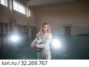 A portrait of a young woman fencer holding her helmet at the school gym. Стоковое фото, фотограф Константин Шишкин / Фотобанк Лори