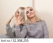 Женщина сидит у зеркала спиной к отражению, показывая жестом пренебрежение. Стоковое фото, фотограф Элина Гаревская / Фотобанк Лори