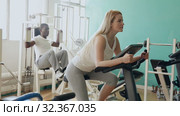 Group of people exercising with weight and on simulators in gym. Стоковое видео, видеограф Яков Филимонов / Фотобанк Лори