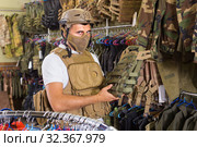 man with flak jacket in hands in airsoft market. Стоковое фото, фотограф Яков Филимонов / Фотобанк Лори