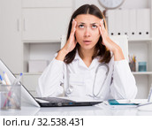 Upset practicioner girl is working with documents and laptop. Стоковое фото, фотограф Яков Филимонов / Фотобанк Лори