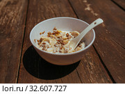 Muesli with banana in white bowl with spoon on a wooden bench. Стоковое фото, фотограф Aleksejs Bergmanis / Фотобанк Лори