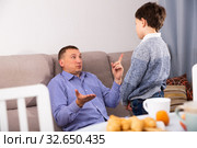 Upset father pointing to mistakes to his son while quarreling. Стоковое фото, фотограф Яков Филимонов / Фотобанк Лори