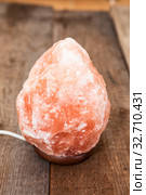 Himalayan electric salt lamp on wooden table from rough timber. Стоковое фото, фотограф Кекяляйнен Андрей / Фотобанк Лори