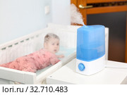 Using humidifier at home, blue ultrasonic device working on table in nursery room. Стоковое фото, фотограф Кекяляйнен Андрей / Фотобанк Лори