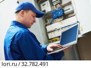 Electrician works with computer laptop near switchbox. Стоковое фото, фотограф Дмитрий Калиновский / Фотобанк Лори