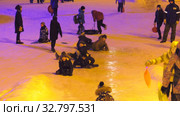 Дети катаются с ледяной горки на городской площади. Children ride on an ice slide in the town square. (2019 год). Редакционное видео, видеограф Евгений Романов / Фотобанк Лори