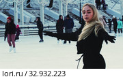 A young pretty blonde woman skating on the ice rink in bright sunlight. Стоковое видео, видеограф Константин Шишкин / Фотобанк Лори