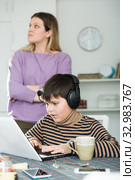 Son plaing video games at laptop, sad mom on background. Стоковое фото, фотограф Яков Филимонов / Фотобанк Лори