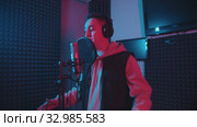A man in headphones rapping in the studio gesticulates while recording his track - neon lighting. Стоковое видео, видеограф Константин Шишкин / Фотобанк Лори