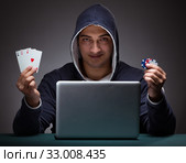 Young man wearing a hoodie sitting in front of a laptop computer. Стоковое фото, фотограф Elnur / Фотобанк Лори