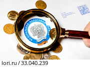 Эмблема Федеральной Налоговой службы Российской Федерации под лупой. Стоковое фото, фотограф Николай Винокуров / Фотобанк Лори