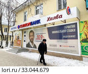 Пожилой мужчина с тростью идет мимо отделения Совкомбанка в городе Кыштым зимой. Россия, Челябинская область (2020 год). Редакционное фото, фотограф Овчинникова Ирина / Фотобанк Лори