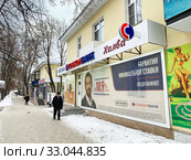 Пожилой мужчина с тростью идет мимо отделения Совкомбанка в городе Кыштым зимой. Россия, Челябинская область (2020 год). Редакционное фото, фотограф Овчинникова Ирина / Фотобанк Лори