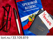 Трудовой кодекс Российской Федерации и трудовая книжка с запиской "Уволить" лежат на столе сотрудника кадровой службы (2020 год). Редакционное фото, фотограф Николай Винокуров / Фотобанк Лори