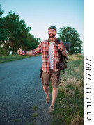 Young smilimg caucasian tourist hitchhiking along a road. Стоковое фото, фотограф Volodymyr Melnyk / PantherMedia / Фотобанк Лори