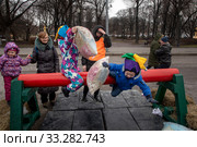 Маленькие мальчики дерутся на бревне подушками в рамках празднования Масленицы в Парке Горького города Москвы, Россия (2020 год). Редакционное фото, фотограф Николай Винокуров / Фотобанк Лори