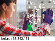 Housework concept, Spring cleanup, young girl in gloves cleaning window with blue rag and spray detergent. Стоковое фото, фотограф Evgenii Mitroshin / Фотобанк Лори