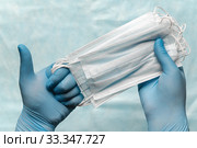 Doctor holding lot medical face mask in hands in blue medical gloves and showing thumb up. Pandemic insurance, grippe, airborne diseases, SARS. Стоковое фото, фотограф А. А. Пирагис / Фотобанк Лори