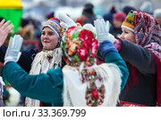 Девушки одетые в национальную старинную русскую одежду и яркие платки водят хоровод на празднике Масленицы. Город Бердск, Новосибирская область, Западная Сибирь, Россия (2020 год). Редакционное фото, фотограф Евгений Мухортов / Фотобанк Лори