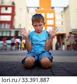 A little boy sits on the ground with his hands up and protests. The concept of raising a difficult naughty child. Стоковое фото, фотограф Александр Сергеевич / Фотобанк Лори