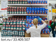 Сотрудник магазина выкладывает упаковки гречки и риса в магазине торговой сети АШАН в торговом центре МЕГА в Химках, Россия (2020 год). Редакционное фото, фотограф Николай Винокуров / Фотобанк Лори