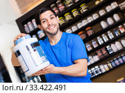 Athletic man seller demostration sport nutrition products in shop. Стоковое фото, фотограф Яков Филимонов / Фотобанк Лори