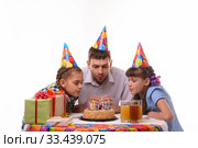 Папа и две дочки дружно задувают свечи на торте. Стоковое фото, фотограф Иванов Алексей / Фотобанк Лори