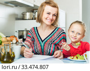 woman and her daughter working with papers from home. Стоковое фото, фотограф Яков Филимонов / Фотобанк Лори