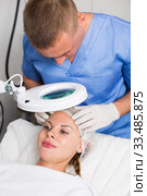 Man doctor is analysing skin on face of female patient before the procedure. Стоковое фото, фотограф Яков Филимонов / Фотобанк Лори