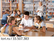 Teenage group of pupils sitting at table and studying. Стоковое фото, фотограф Яков Филимонов / Фотобанк Лори