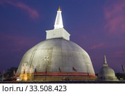 Древняя дагоба Ruwanweli Maha Seya крупным планом в вечерних сумерках. Анурадхапура, Шри-Ланка (2020 год). Стоковое фото, фотограф Виктор Карасев / Фотобанк Лори