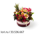 Round burgundy box filled with exotic flowers and fruits on a white background. Стоковое фото, фотограф Олег Белов / Фотобанк Лори