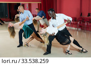 Adult pairs dancing tango movements in modern dance studio. Стоковое фото, фотограф Яков Филимонов / Фотобанк Лори