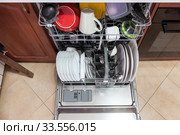 Opened dishwasher with clean plates, spoons and cups is in the kitchen, top view. Стоковое фото, фотограф Кекяляйнен Андрей / Фотобанк Лори