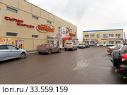 Магазин Народный с припаркованными автомобилями перед ним в пасмурный осенний день. г. Ужур. Красноярский край. Россия. (2017 год). Редакционное фото, фотограф Светлана Попова / Фотобанк Лори