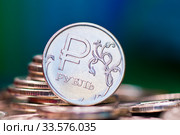Российские деньги. Монета номиналом в 1 рубль среди других рублевых монет на темном сине-зеленом фоне. Стоковое фото, фотограф E. O. / Фотобанк Лори